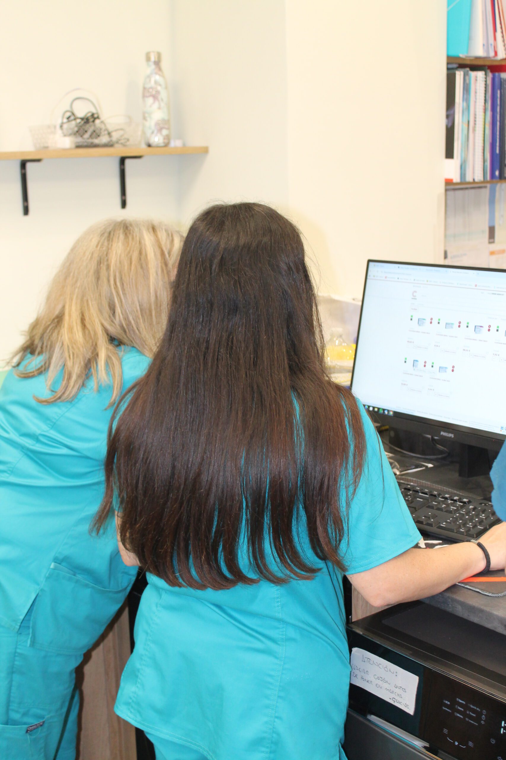Dos enfermeras con uniforme turquesa revisando información médica en ordenador Philips en consulta clínica